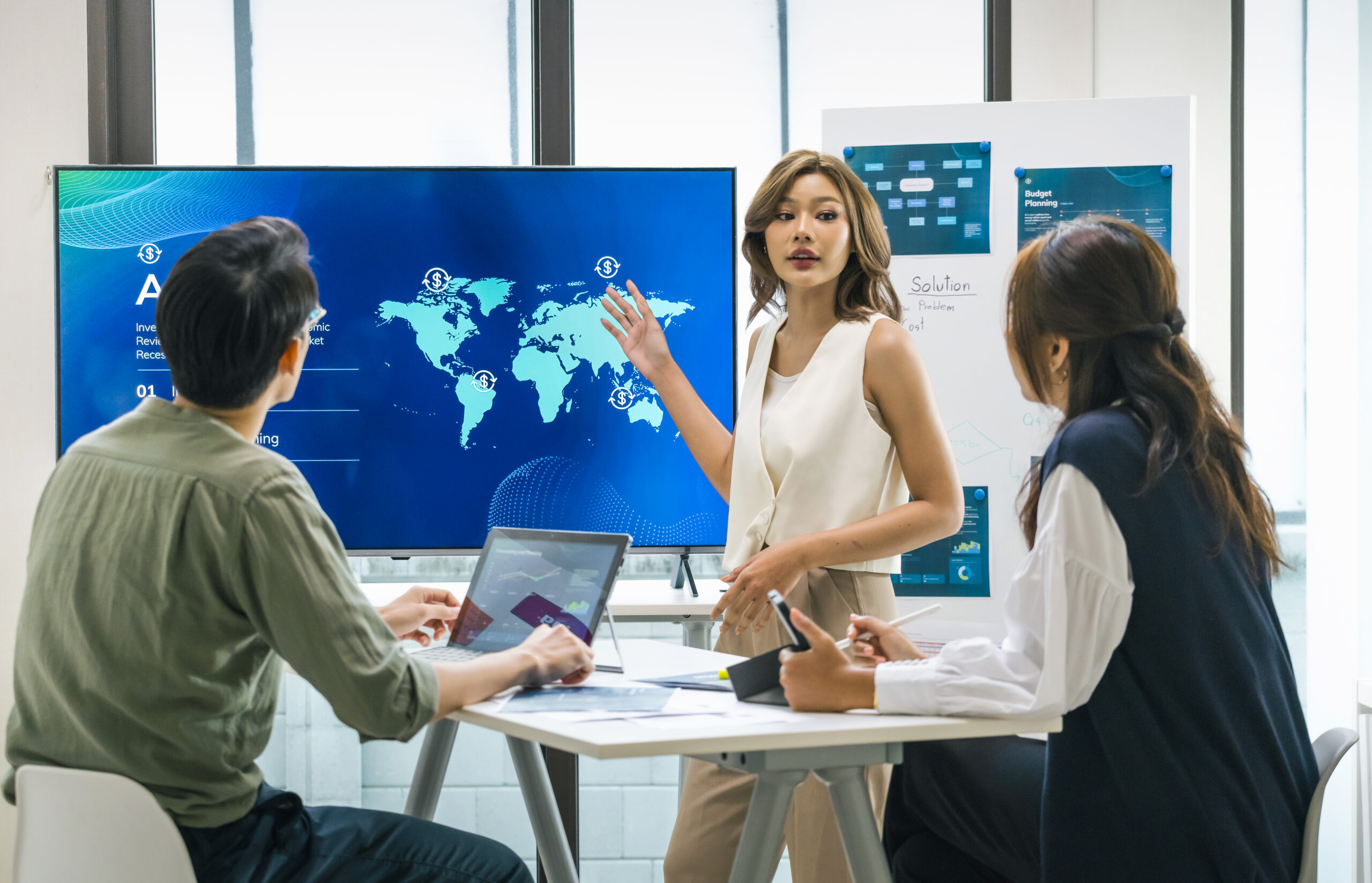 asian leader presenting a financial data and strategies in a modern office with charts and graphs displayed on a large screen